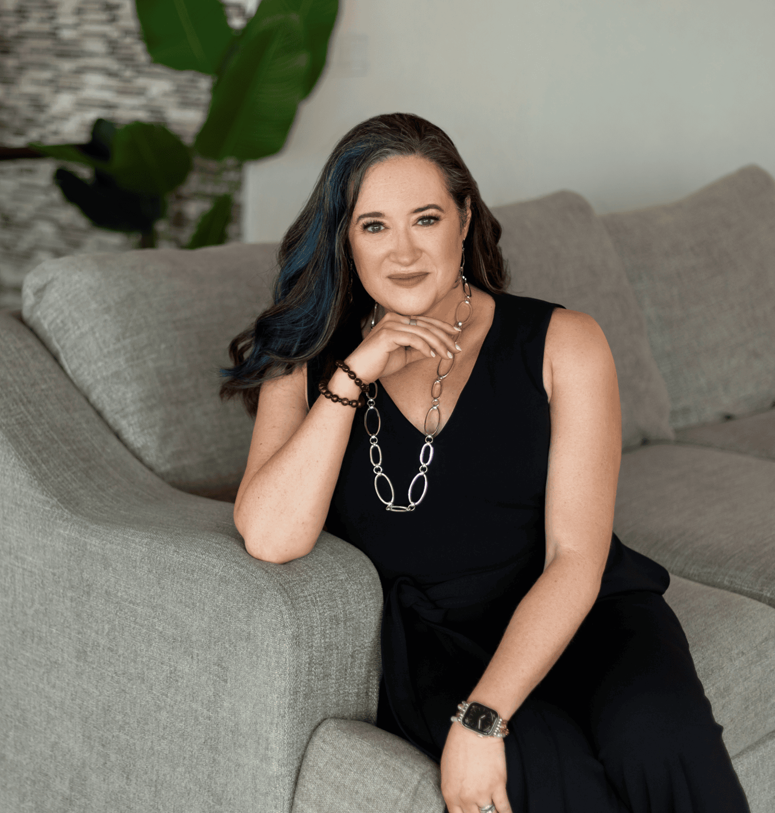 Benah Parker, Ph.D. seated on gray couch in a black outfit, looking composed and thoughtful